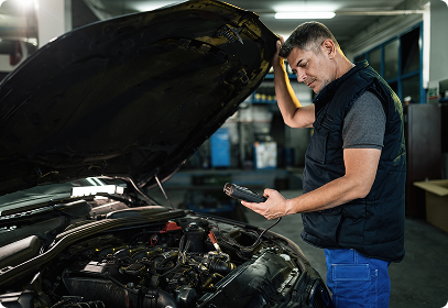 Automotive technician using a diagnostic tablet to inspect a vehicle engine in Winston-Salem NC